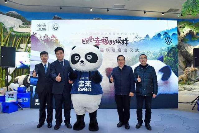 一汽-大众销售有限责任公司副总经理 马振山从中国大熊猫掩护研究中间常务副主任 张和民手中接过印有“熊猫宝来”掌印的合作授权牌