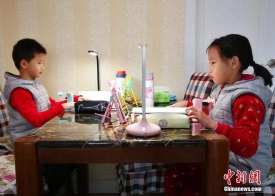 资料图:小学生们正在家中通过电脑、平板电脑等收看直播上课。中新社记者 翟羽佳 摄