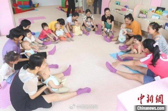 资料图:江西寻乌县一家婴幼儿照护服务指导中心内,工作人员指导家长和幼儿互动做游戏。刘力鑫 摄