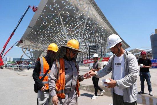 6月12日,在北京城市副中心站综合交通枢纽工程施工现场,北京城建集团的施工人员(左)在领取藿香正气水。新华社记者鞠焕宗 摄