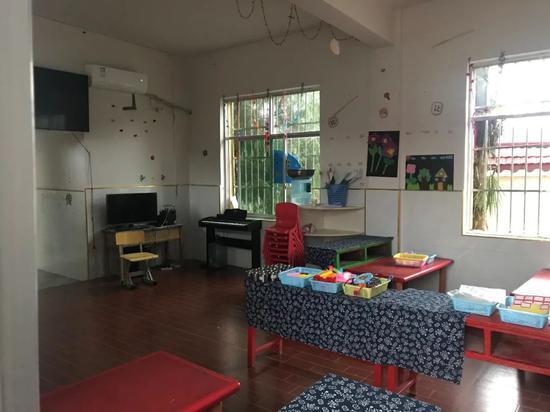 在寨石村乡村幼儿园教室中,课桌摆满了各式玩具和教具。这所幼儿园采用混龄编班的教育方式,老师是当地公开招聘的具有师范背景的志愿者。图/中国发展研究基金会