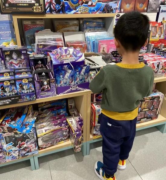 丽雅儿子正在玩具店选购奥特曼卡牌,图据丽雅