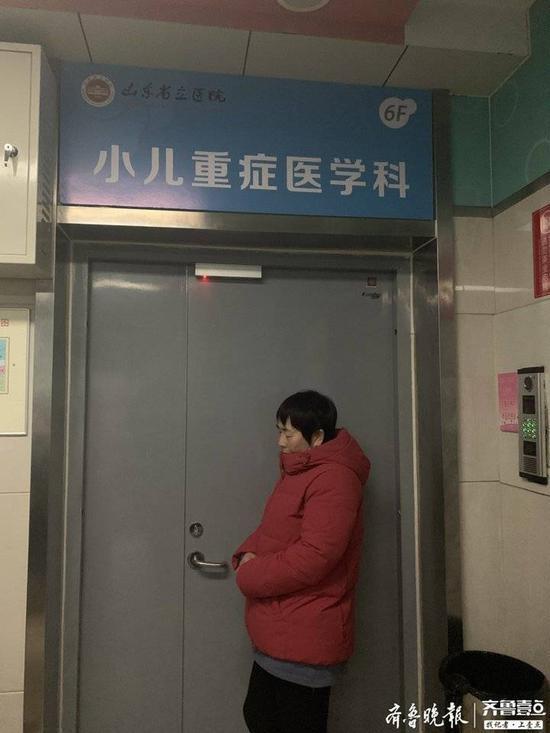 刘军芳(化名)倚在重症监护室大门前 。记者 李震 摄