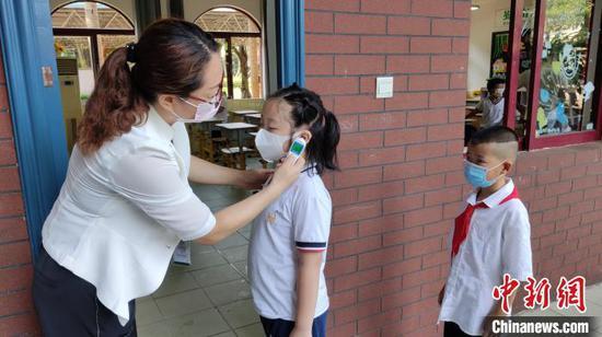 海南枫叶国际学校小学部,学生进教室前进行体温测量。 林士杰 摄