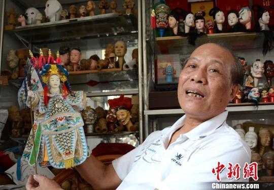 杨亚州展示木偶雕刻的伴手礼。 张金川 摄