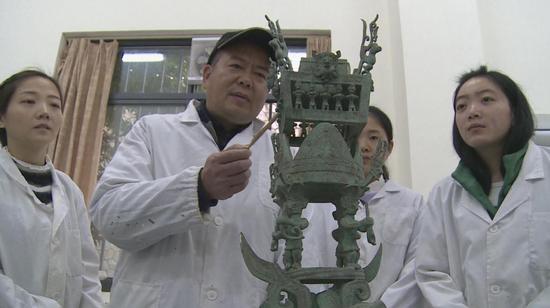 郭汉中与工作人员商讨如何修复文物