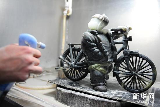 4月7日,在南阳市镇平县“玉雕大师创意园”,工作人员在清洁一件玉雕作品。