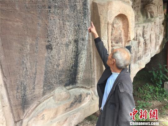 肖太发老人向记者介绍岩石上的碑刻。 何浠 摄