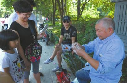 四川博物院外,万富册制作好一个玩具后赠送给了一位小朋友。