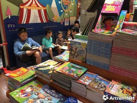在西西弗书店内专门设置的绘本区域,家长陪同小孩在选择、阅读绘本书籍