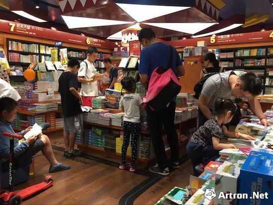 在西西弗书店内专门设置的绘本区域,家长陪同小孩在选择、阅读绘本书籍