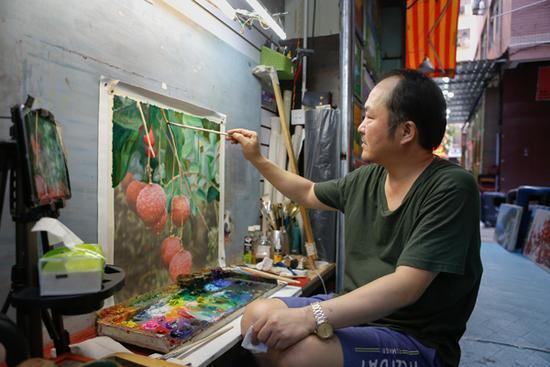 吕彦在给打印的画作上色,偶尔也会画一些行画维持生计。