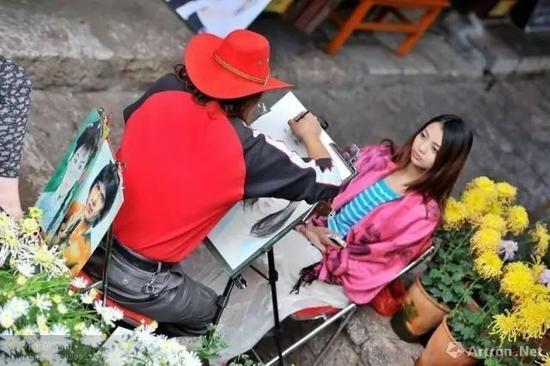 街头一江湖画家正在为一女子画像 图片来源于网络