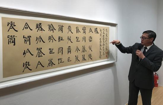 展览现场,澳门艺术博物馆馆长陈继春介绍徐冰的萄文书法作品