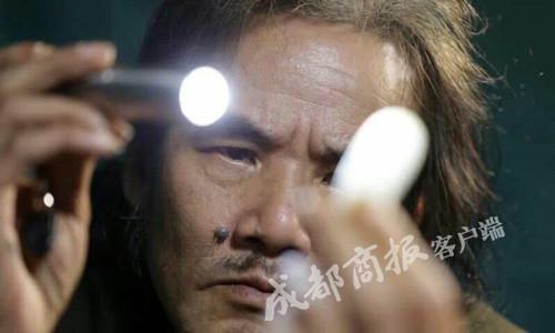 李强在强光灯下,认真检视长江玉(图片来源:成都商报客户端)