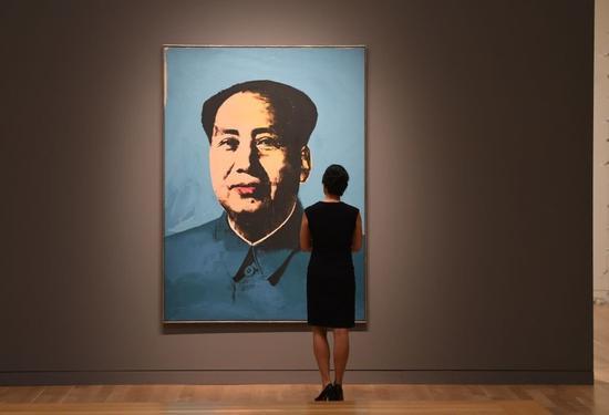 一位女士注视着安迪·沃霍尔的《毛泽东》。图片:TIMOTHY A。 CLARY/AFP/Getty Images