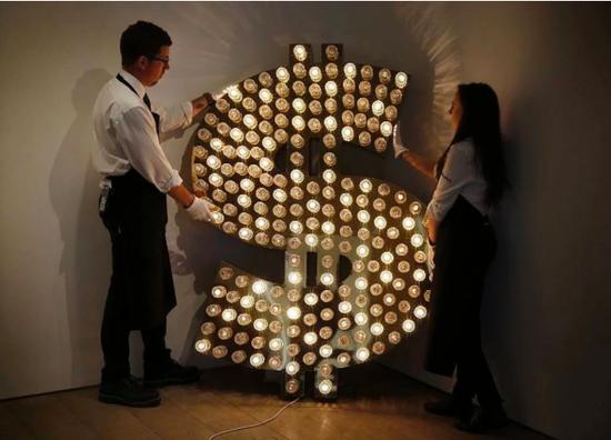 苏富比员工为一幅由Tim Noble和Sue Webster创作的《$》调整位置。图片:Adrian Dennis/AFP/Getty Images