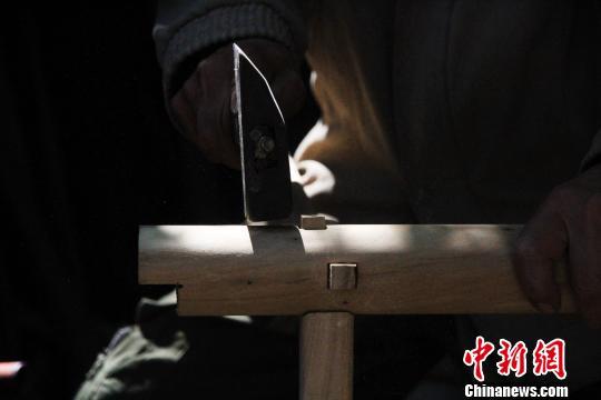 据了解,徐光祥已掌握30余种榫卯结构制作技艺。图为徐光祥组合榫卯结构桌腿。 郝学娟 摄
