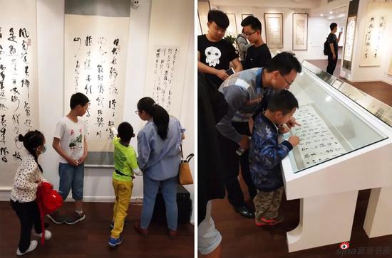 家长带着小朋友也来观展啦。小朋友在很认真的认识草书。