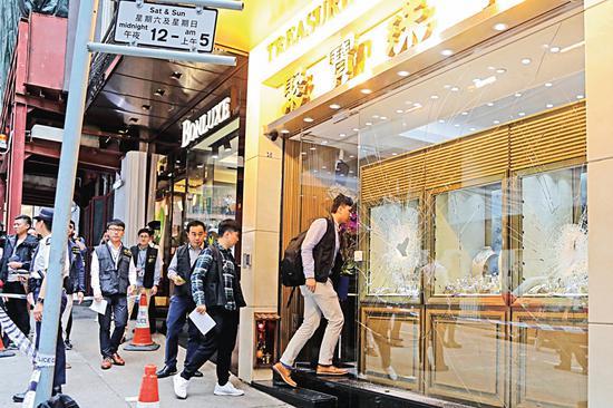 图:中区闹市威灵顿街的一间珠宝店,昨晨遭三名外籍“铁槌贼”抢劫,不消十秒,被劫去4000万元珠宝。图为警员进入珠宝店调查\中通社