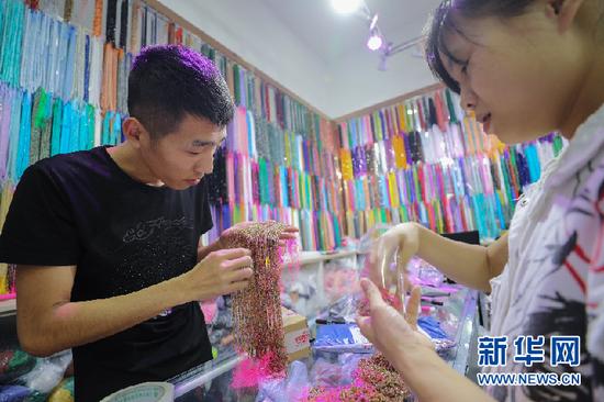 满墙珠串下,来自辽宁的小赵正向顾客介绍自家的水晶。