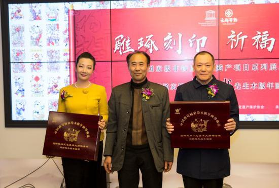 中国非遗保护协会会长马文辉(右)、永新华韵文化产业有限公司总裁张坤兰(左)代表协会与公司接受杨付江先生(中)赠礼