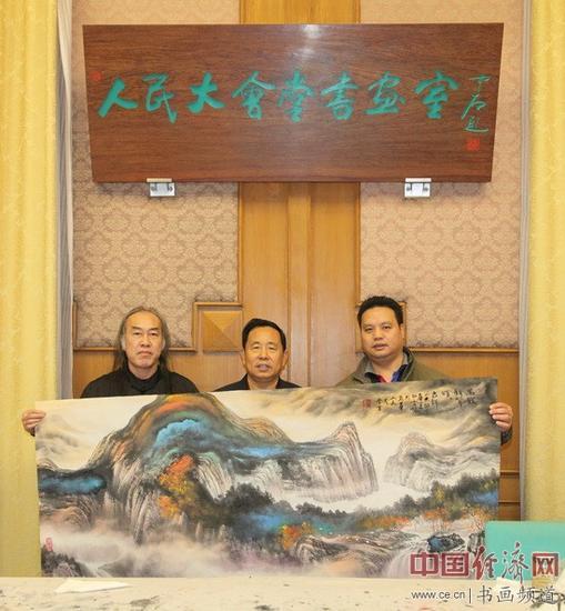 白雪狼(左)现场创作山水画《万籁秋声颂吉祥》后,与李景祥(中)、梁建忠(右)合影。