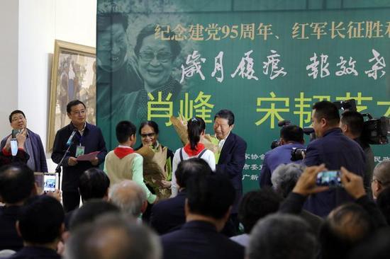 “岁月履痕,报效桑梓——肖峰、宋韧艺术展”开幕现场,少先队员给两位老艺术家献花