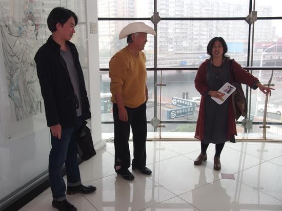 窦红向父亲窦培高及儿子窦剑介绍画展
