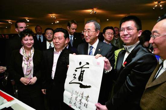 2007年3月,吴欢在联合国总部举办“吴氏家族中国书画展”,时任联合国秘书长潘基文亲临开幕式并致辞。图为潘基文(中)接受吴欢(左二)赠送的书法作品“道”。