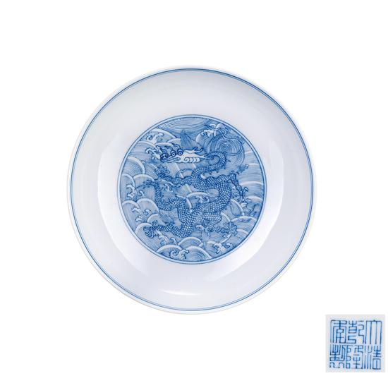 005 清乾隆 青花海水纹龙盘 本品纹饰为仿明宣德青花海水龙纹盘所製。盘心以淡描青绘海水龙纹,外壁以青花绘海水纹,整器器型规整,画工工整,青花发色淡雅,胎质细腻,白釉温润。底落“大清乾隆年製”六字三行篆书款。 Qianlong Reign Period of Qing Dynasty, Blue-and-white sweater stripe dragon plate D:17.5cm RMB: 60,000-100,000