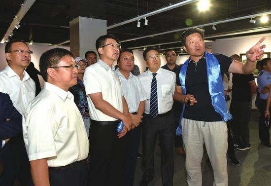 中国美术家协会油画艺术委员会秘书长、中国艺术研究院中国油画院副院长徐青峰(右一)为嘉宾介绍展览作品
