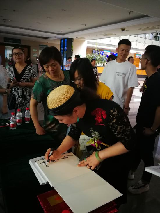 图为李采姣教授为来宾亲笔题字