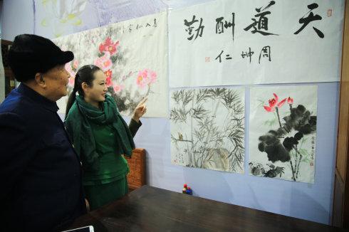 张凡凡向周坤仁上将介绍书画作品