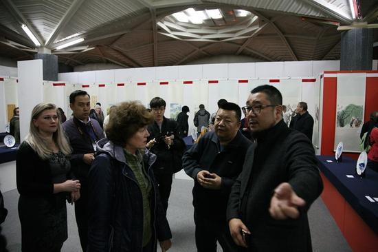 哈萨克斯坦阿拉木图市哈萨克斯坦国家中心博物馆展览现场内《艺术市场》杂志社股份有限公司副总经理、《艺术市场》美术馆馆长李学伟(右一)向嘉宾介绍展览作品