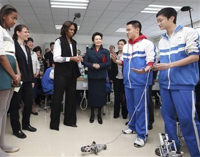 彭丽媛与米歇尔观看学生们演示自己设计制作的几何机器人。