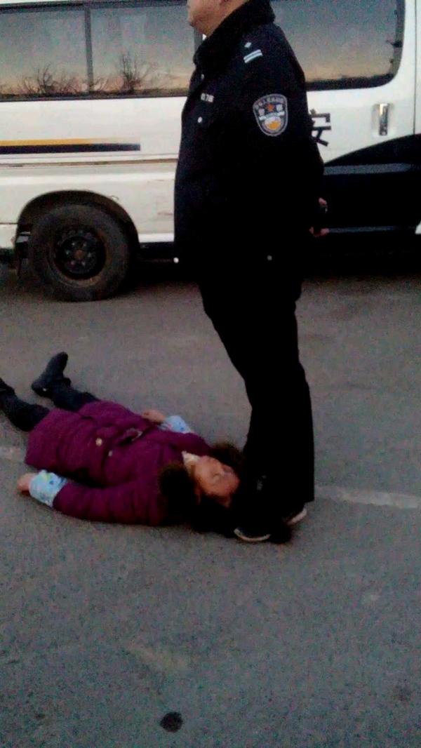 事发现场一名身穿警服的男子疑似用脚踩着女农民工周秀云的头发(12月13日摄)。