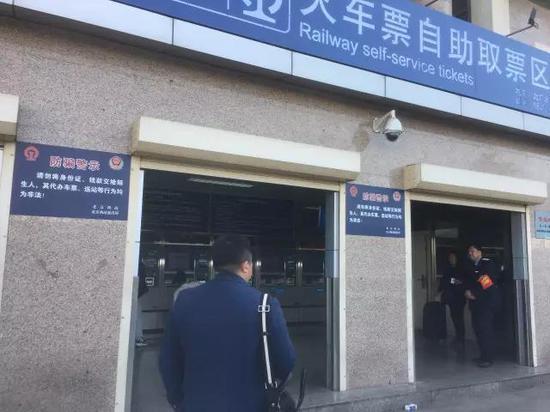 北京西站,北广场取票处张贴着提示牌,一名检查员站在取票处执勤。