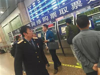 北京西站,在北广场的售票大厅内有工作人员不停巡视取票处。