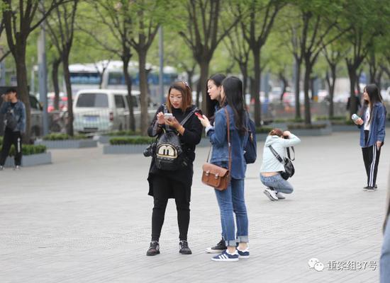 2017年4月19日,北京三里屯,行骗人(右边黑色上衣)问被拍女性要联系方式,身后另一位行骗人半蹲在给人拍照。