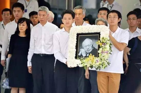 李显扬长子李绳武(举遗照左)和李显龙次子李浩毅(举遗照右)。(网络图)