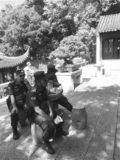 景区保安拿着喇叭对着“合唱团”播放“文明公约”。