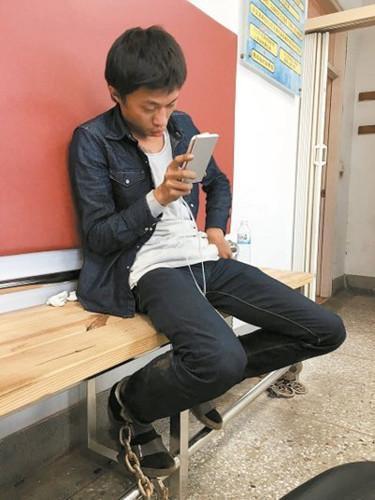 大货车司机陈君玮,在派出所滑手机。图自台湾《联合报》