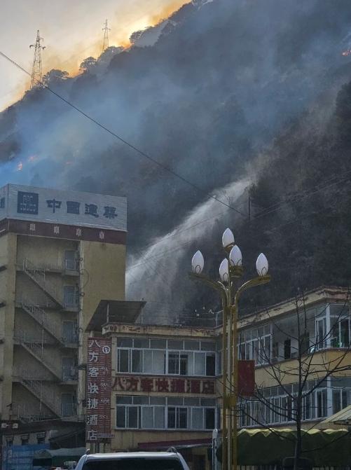 在距离雅江县城四五公里处可以看见明火，还有消防队员在喷射水枪灭火。上游新闻记者 李文滔 摄