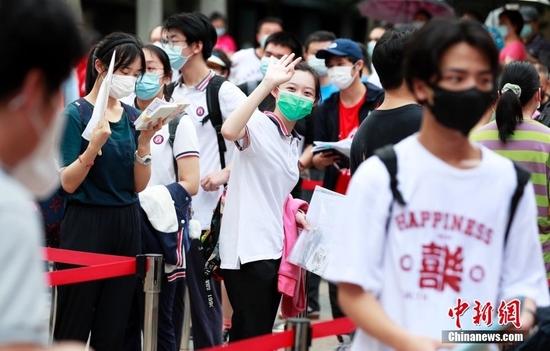 资料图:一名考生在进入考场前向家长挥手致意。 中新社记者 汤彦俊 摄