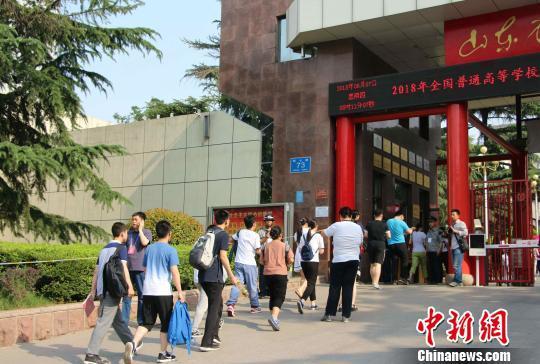 资料图:6月7日,2018年夏季高考启幕,考生们拿着准考证陆续通过安检进入考场。 赵晓 摄
