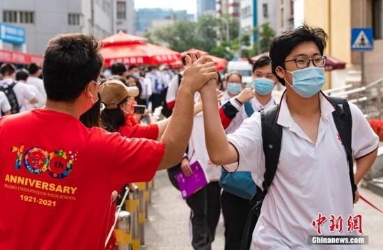 6月7日上午,北京市朝阳区陈经纶中学考点外,参加高考的学生入场前与送考老师击掌。当日,2022年全国高考拉开帷幕。 中新社记者 侯宇 摄