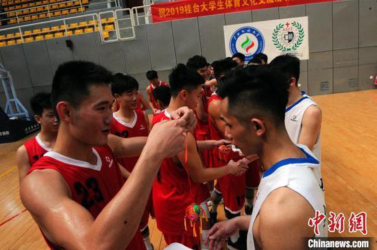 广西民族大学篮球队队员给台湾辅仁大学篮球队队员赠送壮族吉祥物绣球。 蒋雪林 摄