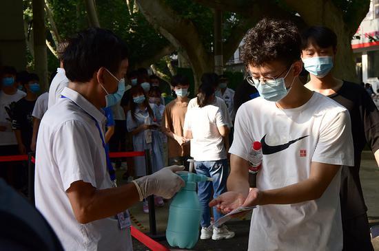 研判后疫情时代走势并制定高考方案时,决策者应当叩问自身是否铭记了公平性这一深层次问题。图为7月7日,河南郑州,2020年高考一考点,考生进入考场前进行消毒。 新华社记者 朱祥 摄