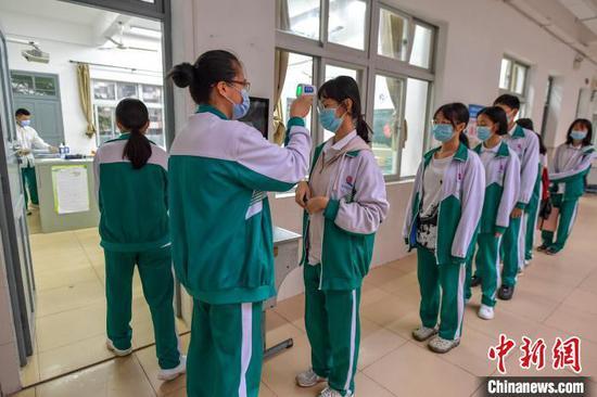 海南华侨中学学生在进入教室前有序测量体温。 骆云飞 摄